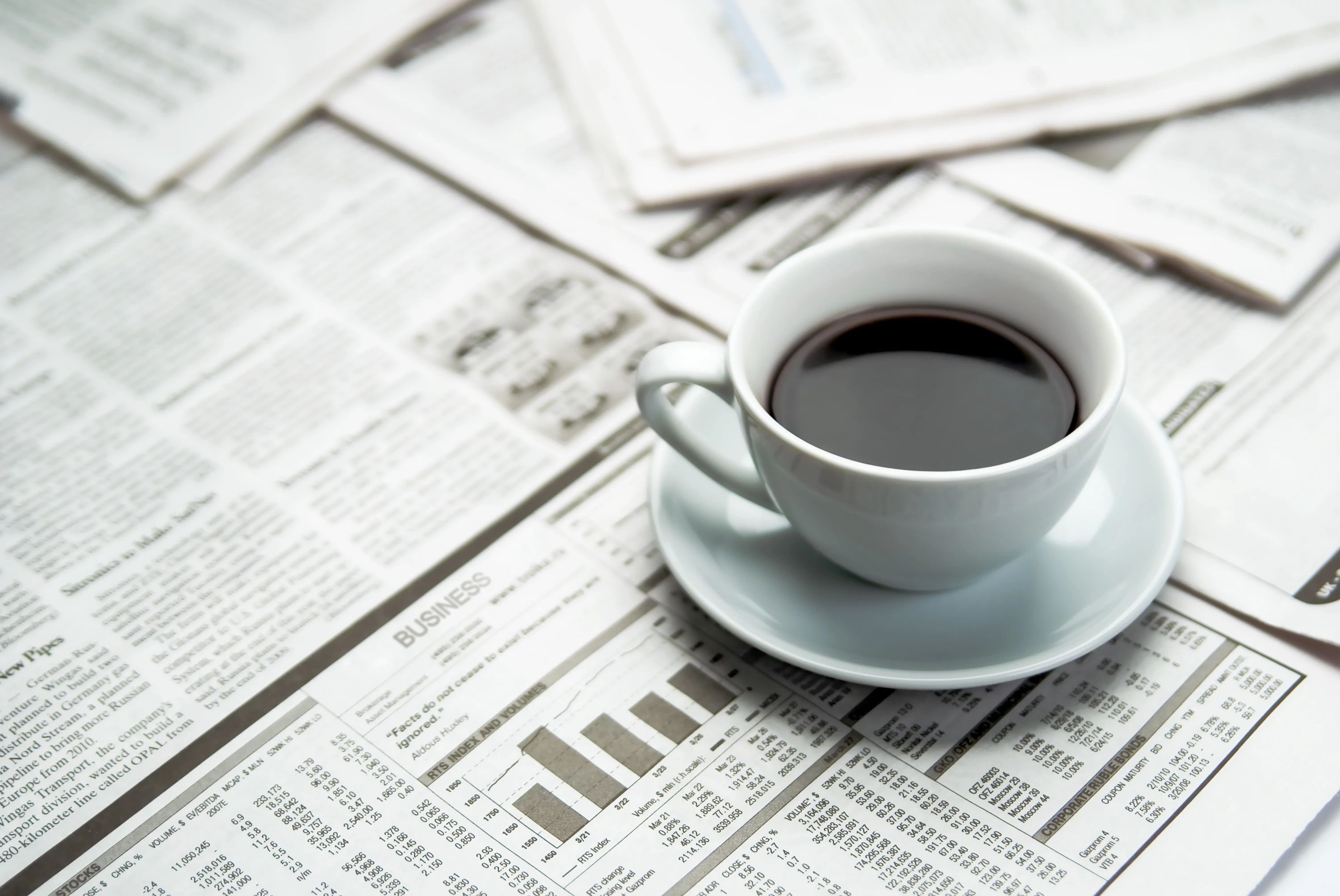 cup of coffee on a table full of newspapers - Shop at Carpet On Wheels in the Jamesburg, NJ area from the comfort of your home
